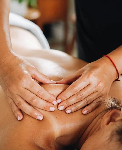 Close-up of hands giving a back massage to a person lying face down on a massage table.