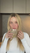 A woman with long blonde hair uses the iS Clinical Active Peel System by iS Clinical in a modern kitchen.